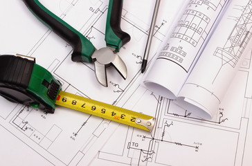 Work tools and rolls of diagrams on construction drawing of house