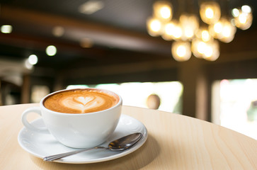 Hot art Latte Coffee in a cup on wooden table and Coffee shop bl