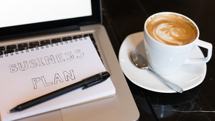 Workplace, laptop and notepad with hand drawn business plan sele