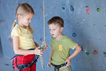 brother and sister standing near a rock wall for climbing
