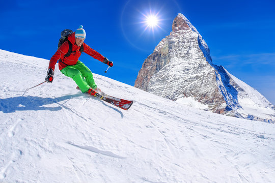 Skier skiing downhill against Matterhorn peak in Switzerland