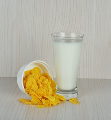 Corn flakes and glass of milk on wooden background