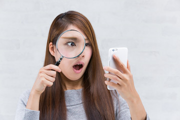 虫眼鏡でスマートフォンを覗く女性