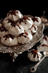 Sweet meringue cookies with chocolate on a silver tray