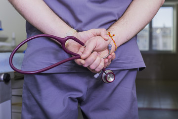 Dr. hands behind his back holding stethoscope