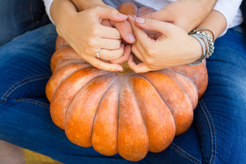 Сouple sitting embracing each other and holding a pumpkin on his lap