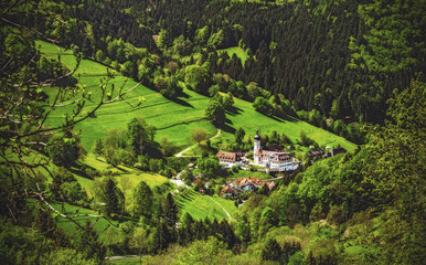 Fototapeta na wymiar Scenic panoramic landscape: summer mountain valley with forests, fields and old church in Germany, St. Ulrich, Black Forest