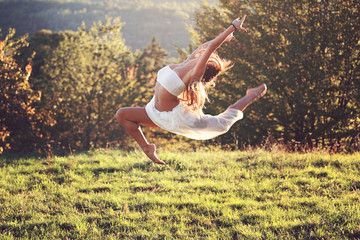 Beautiful gymnast in a difficult jump outdoor