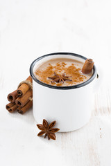 Masala tea in a cup and ingredients on wooden table