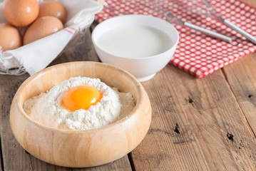 Egg yolk in the flour with milk and whip for beating on wood tab