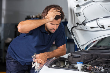 Mechanic Examining Car Engine At Repair Shop