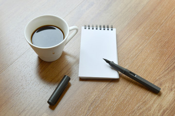 Coffee cup, spiral notebook and pen on the laminate floor backgr