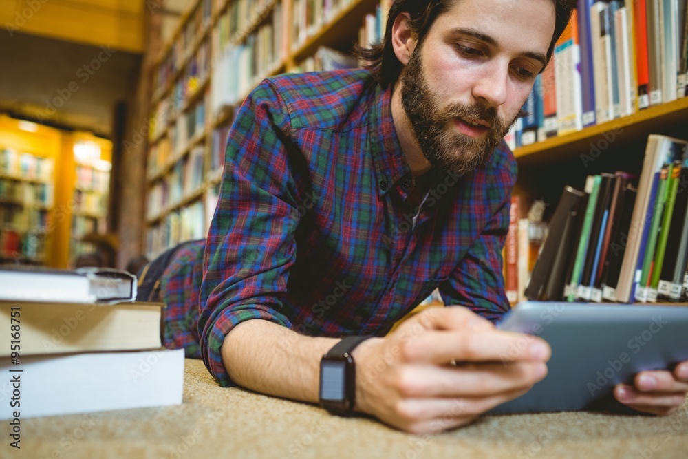 Wall mural student studying on floor in library wearing smart watch