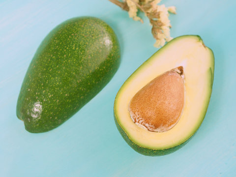 Green pastel wooden background with avocado cut in two parts