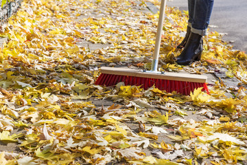 Herbstlaub fegen auf Bürgersteig