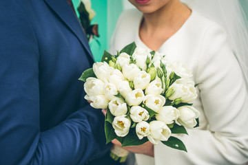 groom and bride holding beautiful white tulip bouquet