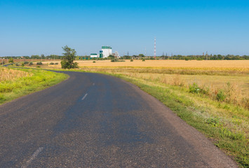 Fototapeta na wymiar Rural road leading to grain elevator in Bozhkove village, in Poltavskaya oblast, Ukraine