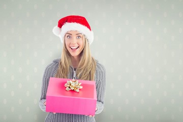 Composite image of festive blonde holding christmas gift