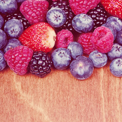 Assorted fresh juicy berries on wooden background, close-up.Special toned photo in vintage style
