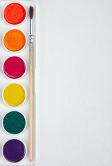 paints for painting and brush on blank white paper sheet