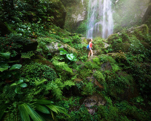 Fototapeta premium Young backpacker traveling along jungles, on background waterfal