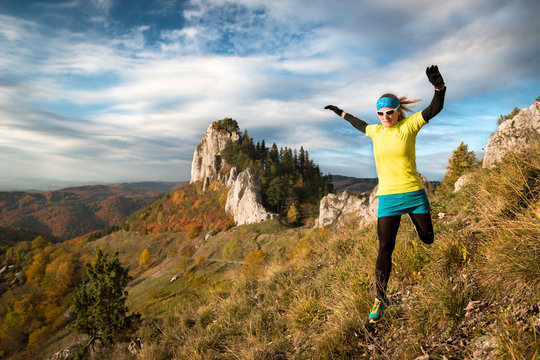 young woman in skirt jumping on a rocky trail with scenic view