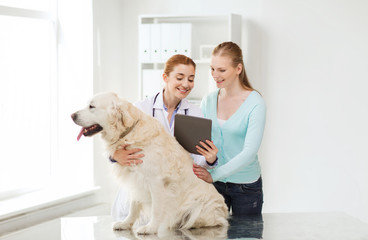 happy woman with dog and doctor at vet clinic