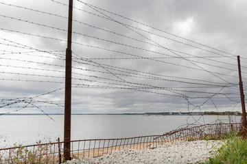 barb wire fence over gray sky and sea