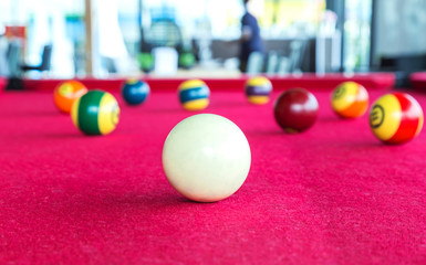 Naklejka na ściany i meble Closeup focus snooker white ball with pool balls behind on red table. 