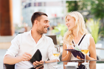 happy couple with wallet paying bill at restaurant
