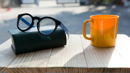 Yellow glass of coffee and glasses on wooden table