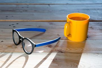 Yellow glass of coffee and glasses on wooden table