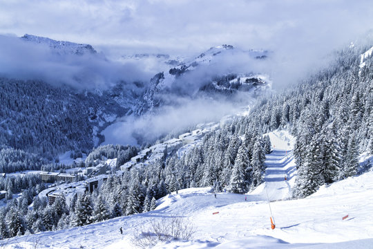 Top view of French skiing resort Flaine in Grand Massive in Alps with chalets, apartment blocks, pine forest and slopes, on a foggy winter day