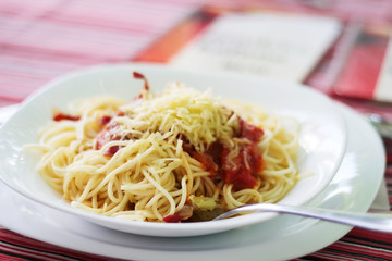 Spaghettis with cheese and ketchup on a white plate,  selective focus