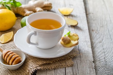 Ginger tea and ingredients on rustic wood background