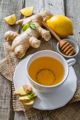 Ginger tea and ingredients on rustic wood background