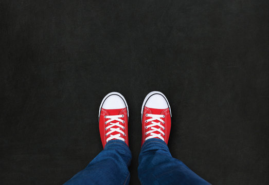 Feet wearing red shoes on black background with space for text