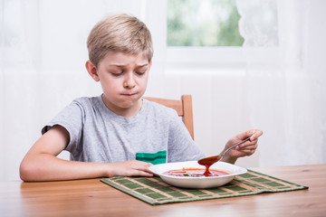 Child eating soup with disgust