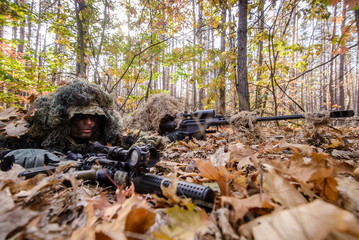 Pair of masked snipers in forest/Two soldiers in sniper camouflage lying on eaves in forest with rifles