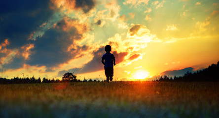 Cheerful boy running towards the sunset