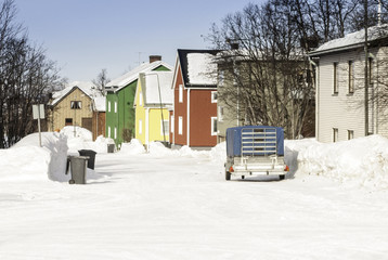 Naklejka premium Brightly coloured houses in a snow-bound street in Swedish Lapland.