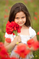 Close up of cute girl in poppy field holding flowers bouquet. Adorable little girl in poppies. Happy kid with poppies outdoors