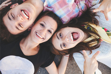 Closeup of three best friends lying down and laughing. Teenage people wearing casual clothes...