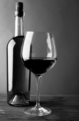 Bottle of white wine and a glass on wooden table,  black and white retro stylization
