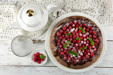 Cake with Chocolate Glaze and raspberries and cup of tea on color wooden background