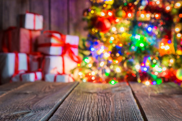 Christmas background with old wooden table, light bokeh and presents.
