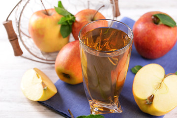 Glass of apple juice with fruits and fresh mint on table close up