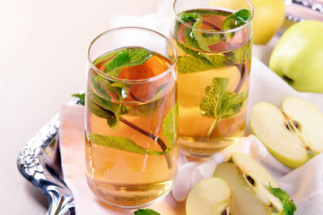 Glasses of apple juice with fruits and fresh mint on table close up
