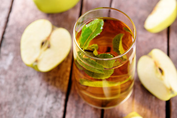 Glass of apple juice with fruits and fresh mint on table close up
