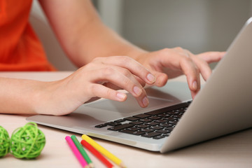 Woman using laptop on workplace close up